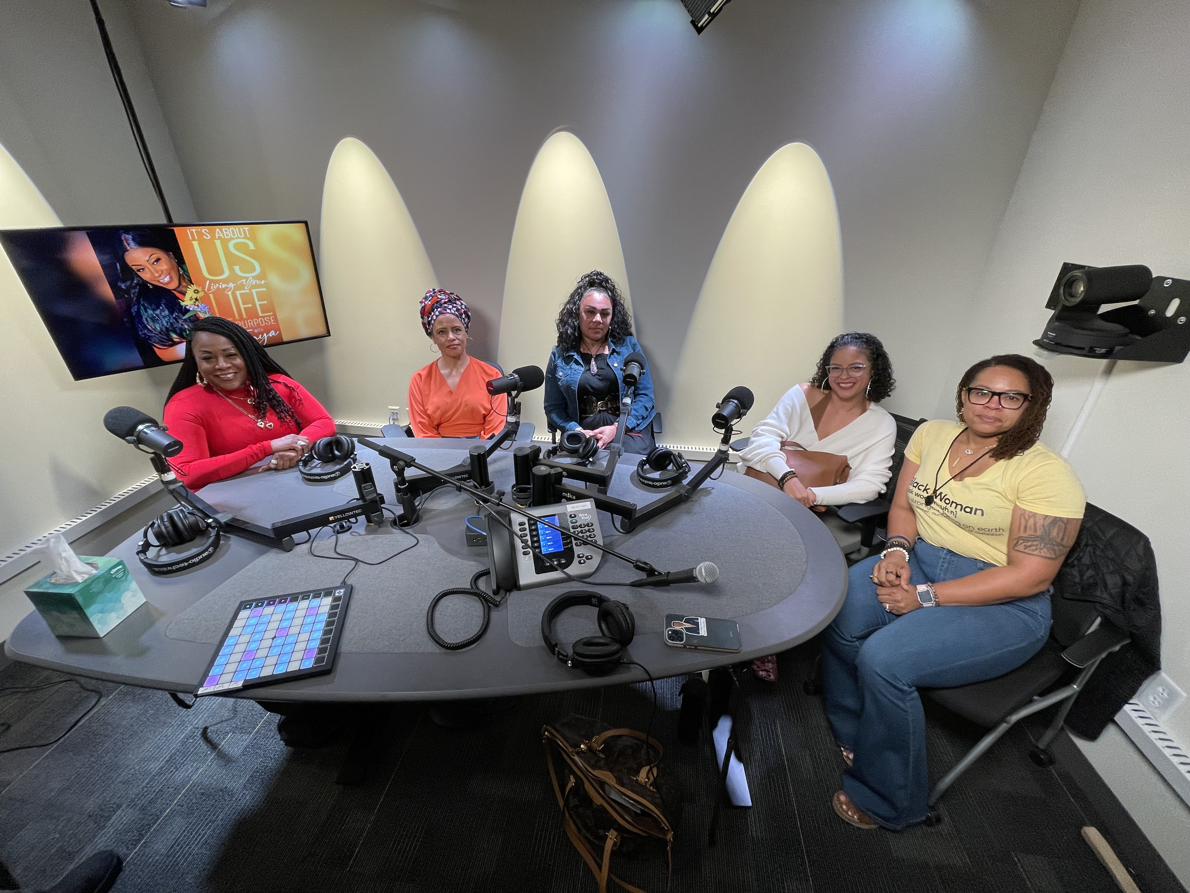 5 women sitting in a podcast studio smiling